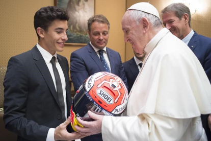 Marc Márquez le entrega uno de sus cascos al Papa Francisco en presencia de Emilio Alzamora
