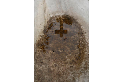 Una cruz se refleja en una lápida en el cementerio de León. FERNANDO OTERO