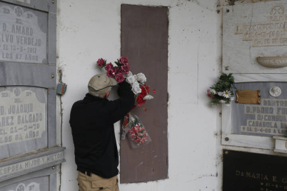 Vicente Iban coloca unas flores depositadas por algún familiar en la puerta uno de los osarios del Cementerio. FERNANDO OTERO