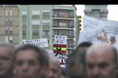 Banderas de España con crespones negros e improvisados escritos, entre las cabezas de los manifestantes.