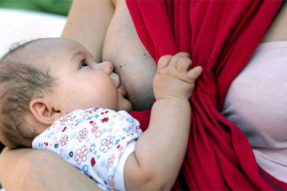 Una mujer, dando el pecho a su bebé.