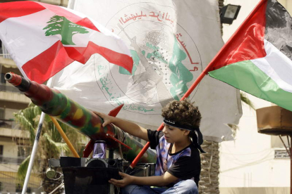 Un niño libanés sentado junto a un cohete durante una manifestación de seguidores de Hamas.