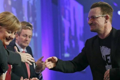 Bono, el cantante de U2, saluda a la cancillera alemana, Angela Merkel, este viernes en la clausura del congreso del PPE.