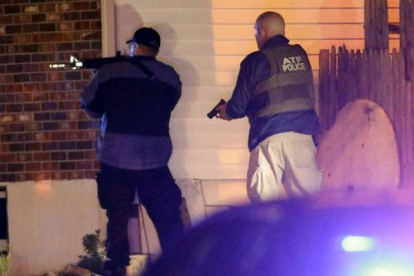 Dos de los policías, apuntando con sus pistolas durante el dispositivo. Matt Rourke | AP