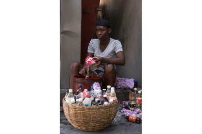 Una mujer haitiana llena botellas con gasolina para vender. ORLANDO BARRIA