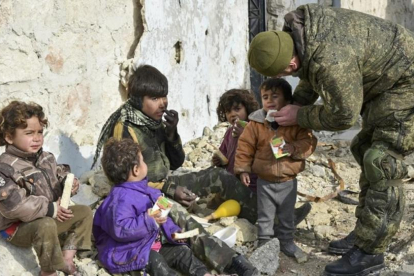 Un soldado ruso atiende a unos niños sirios en Aleppo, Siria.