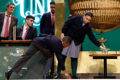 Uno de los niños de San Ildefonso recoge la bola que se le ha caído durante el sorteo extraordinario de Navidad de la Lotería Nacional este viernes en el Teatro Real de Madrid. JJ GUILLÉN