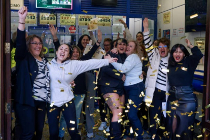 Varias personas celebran en la sucursal Doña Manolita de Madrid, que ha vendido décimos de los números 01568 y 88979, dos de los quintos premios, durante la celebración del sorteo extraordinario de Navidad de la Lotería Nacional, este viernes. EFE