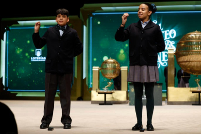 Dos niños de San Ildefonso cantan el primer quinto premio del sorteo, el 54.274, durante el sorteo extraordinario de Navidad de la Lotería Nacional este viernes en el Teatro Real de Madrid. JJ. GUILLÉN
