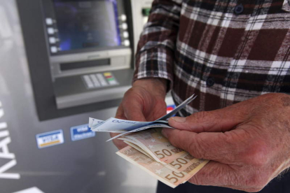 Un hombre muestra dinero tras pasar por un cajero automático. KATIA CHRISTODOULOU