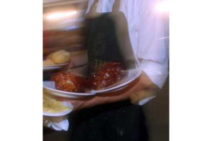 Un camarero lleva varios platos a una mesa.