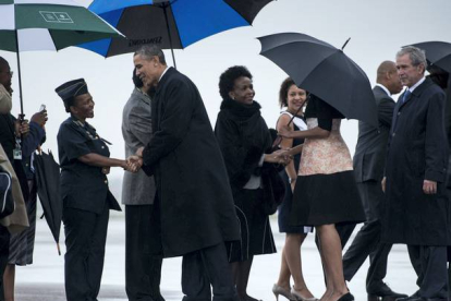 El presidente de EEUU, Barack Obama, recibido en su llegada, junto a la primera dama Michelle Obama y al expresidente norteamericano George W. Bush. BRENDAN SMIALOWSKI | AFP