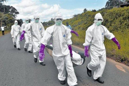 Personal protegido con trajes especiales retira el cuerpo de un fallecido por ébola en Monrovia (Liberia).