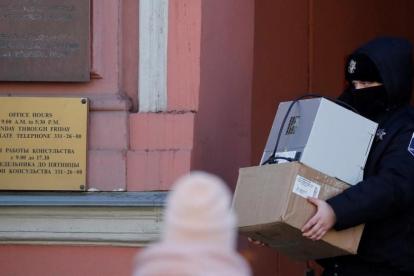 Un agente de seguridad carga con varias cajas a su salida del Consulado General de EEUU en San Petersburgo.