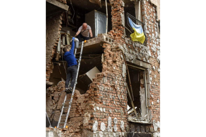 Una familia recoge sus pertenencias en un bloque de apartamentos destruido en Irpin. OLEG PETRASYUK