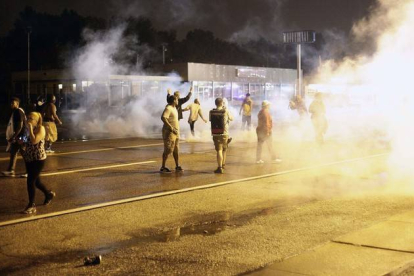 Manifestantes protestan por las calles de Ferguson entre columnas de humo, este sábado por la noche.