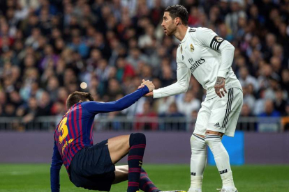 El defensa del Real Madrid Sergio Ramos ayuda a levantarse a Gerard Piqué en un Clásico. RODRIGO