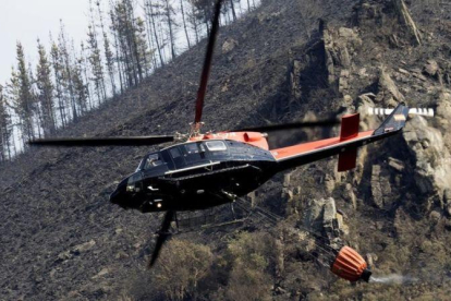 Un helicóptero sobrevuela el área castigada por las llamas en el incendio forestal declarado en la parroquia de San Tomé de Cervantes, en Lugo.