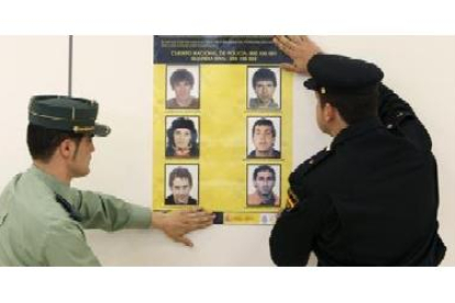 Un guardia civil y un policía cuelgan, el año pasado, un cartel con los etarras más buscados.