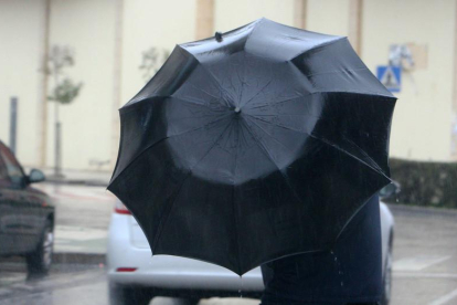 Un hombre se protege del viento y la lluvia en Ponferrada