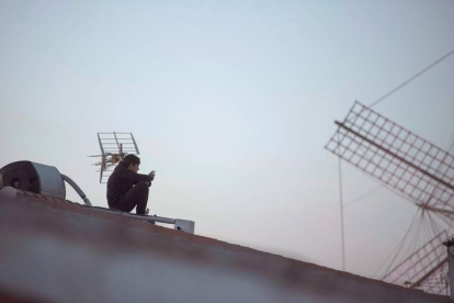 Un joven utiliza su teléfono en un tejado, en Menorca. DAVID ARQUIMBAU SINTES