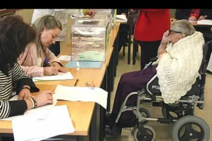Una leonesa centenaria observa como sus papeletas son depositadas en la urna electoral.