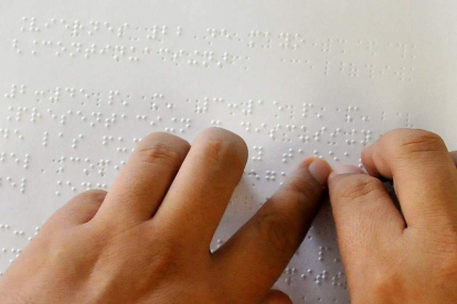 Una persona ciega lee un texto en braille gracias a la ayuda de las manos.