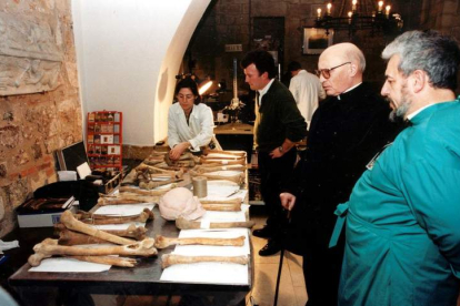 Imagen del abad Viñayo con tres de los investigadores del proyecto científico y ante parte de los restos óseos hallados. NORBERTO