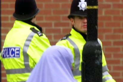 Una mujer musulmana pasa junto a dos policías británicos.