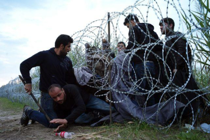 Refugiados sirios entran en Hungría por debajo de la valla de la frontera húngara