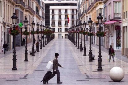 Sólo algunos viandantes cruzan por las calles de una Málaga vacía.