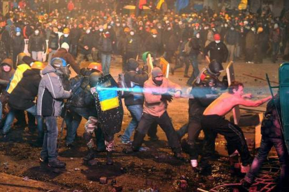 Unos manifestantes chocan con la policía antidisturbios durante una manifestación de la oposición en el centro de la capital ucraniana. 200.000 manifestantes expresaron su frustración por la falta de un programa claro de los líderes de la oposición, después de casi dos meses de protestas, contrarios al acuerdo económico con Rusia y partidarios de la adhesión a la Unión Europea. AFP PHOTO / GENYA SAVILOV