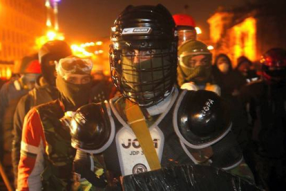 Manifestantes vestidos con equipo de protección improvisada se preparan para enfrentarse con la policía en el centro de Kiev . AP / SERGEI GRITS