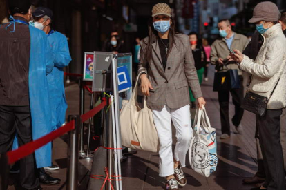 La gente escanea códigos QR de salud para ingresar al área de compras, en Shanghai, China. FIRMA