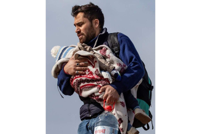 Un hombre intenta pasar la frontera turca con su hijo.