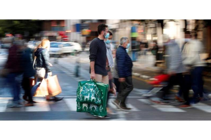 Un grupo de personas cargan en Valencia con sus bolsas tras realizar sus compras a días de celebrarse la Navidad. KAI FÖRSTERLING