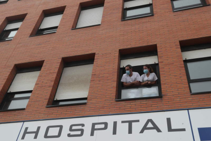 Dos profesionales en una de las ventanas de la fachada del hospital, en imagen de archivo. ANA F. BARREDO