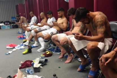 Los jugadores de Argentina, pendientes de sus teléfonos móviles tras la victoria sobre Venezuela.