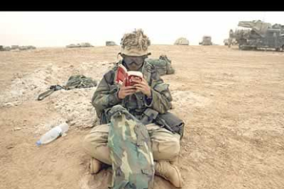 Un soldado, cubierto de arena, aprovecha para leer su libro en el sur de Irak.