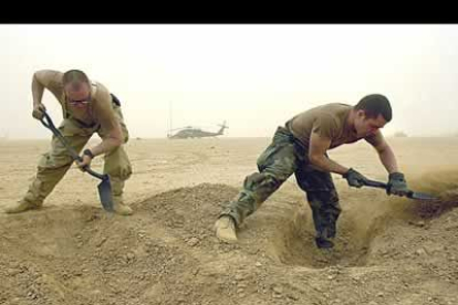 Dos miembros de las tropas de Aviación en el sur de Irak trabajan en la limpieza de la zona tras la tomenta.