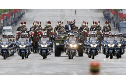 Macron saluda desde un vehículo militar a su paso por los Campos Elíseos.