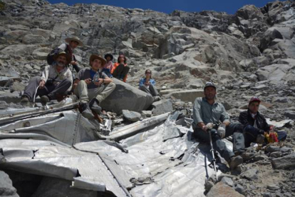 Los alpinistas posan con los restos del avión siniestrado.