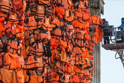 Asistentes del artista Ai Weiwei colocan chalecos salvavidas en la Kinzerthaus de Berlín, en recuerdo de los refugiados.