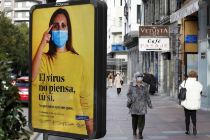 Una calle de Oviedo con un cartel de la campaña contra el coronavirus en Asturias. J. L. CEREIJIDO