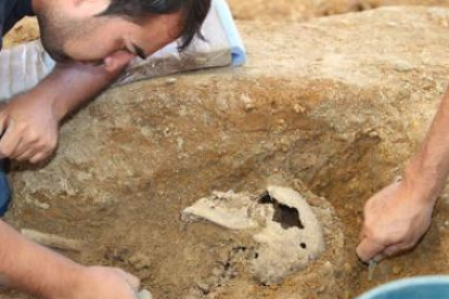 Un voluntario aparta tierra de los huesos de la escápula, durante la exhumación del cadáver.