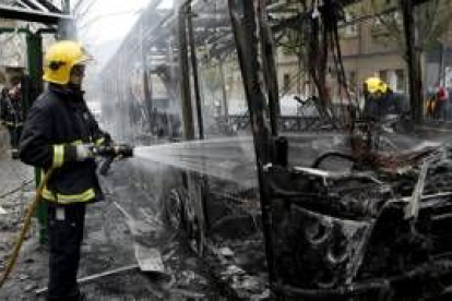 Un bombero apaga el autobús incendiado por encapuchados en el barrio bilbaíno de Santutxu