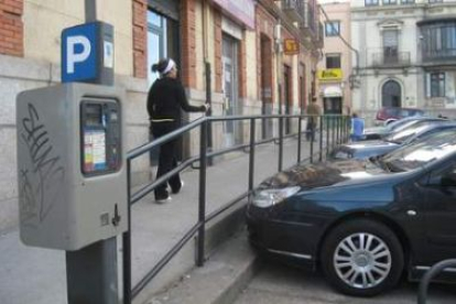 Una joven camina junto a varios vehículos aparcados en una zona regulada por la ORA