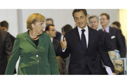 Angela Merkel y Nicolas Sarkozy se dirigen hacia la sala de conferencias tras mantener un primer encuentro en Berlín.