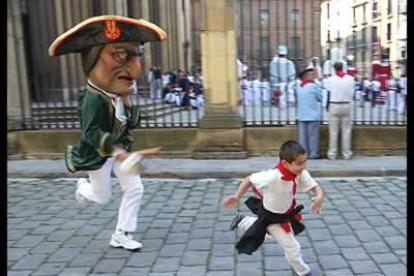 Un tradicional cabezudo persigue a un niño por las calles de la ciudad, que estos días se viste de fiesta.