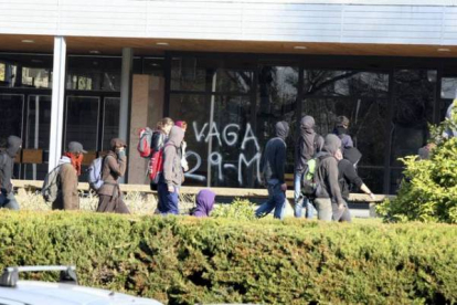 Estudiantes pasan por delante de un edificio con una pintada de apoyo a la huelga. Foto. DANNY CAMINAL